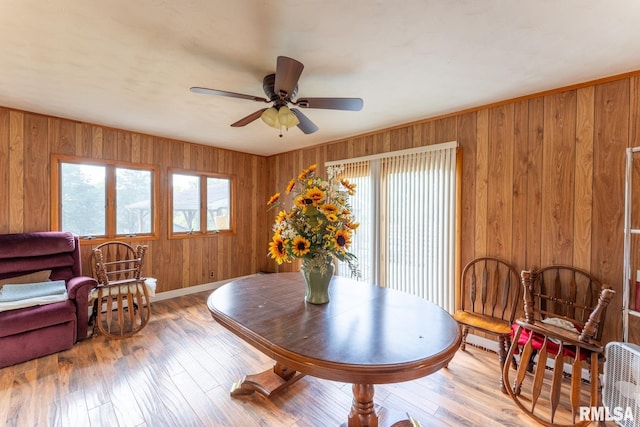 dining room featuring wood walls, light hardwood / wood-style floors, and ceiling fan