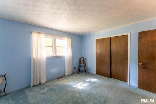 unfurnished bedroom featuring carpet floors, wooden walls, and a closet