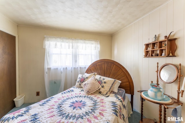 carpeted bedroom featuring a textured ceiling, wood walls, and crown molding