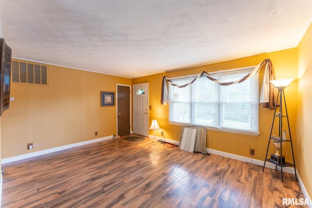 empty room with wooden walls and dark hardwood / wood-style floors