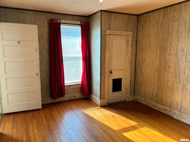 unfurnished room with hardwood / wood-style flooring and wooden walls