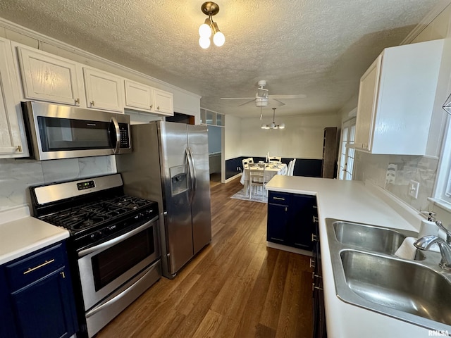 kitchen with appliances with stainless steel finishes, dark hardwood / wood-style flooring, sink, blue cabinetry, and white cabinets