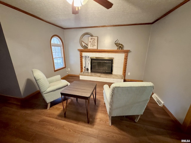 living area with hardwood / wood-style floors, ceiling fan, a fireplace, and a textured ceiling