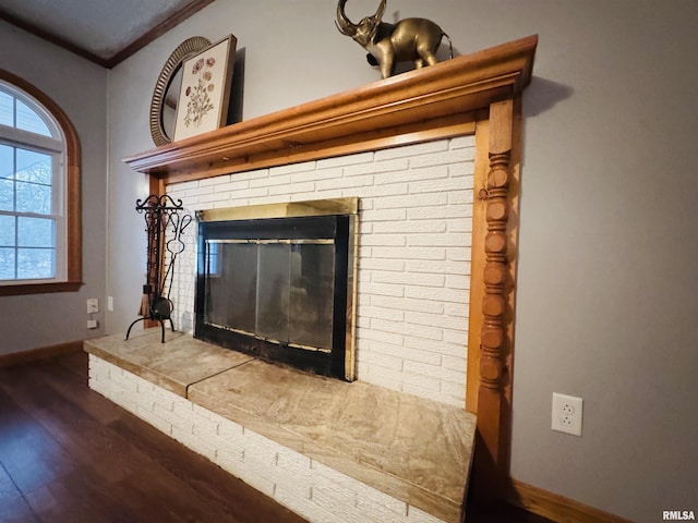 room details with hardwood / wood-style floors, ornamental molding, and a brick fireplace