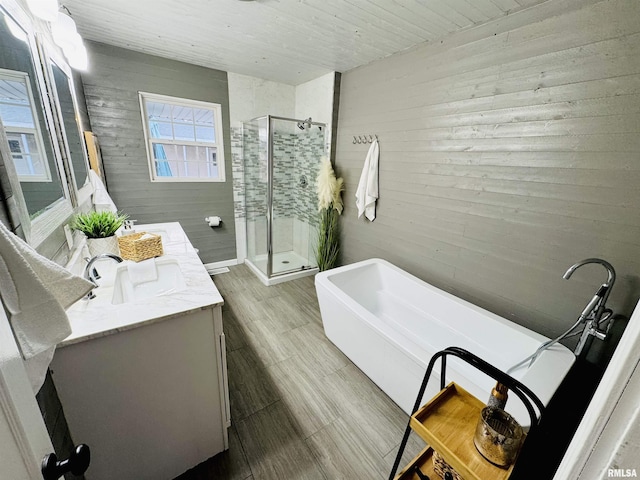 bathroom featuring vanity, separate shower and tub, and wood walls