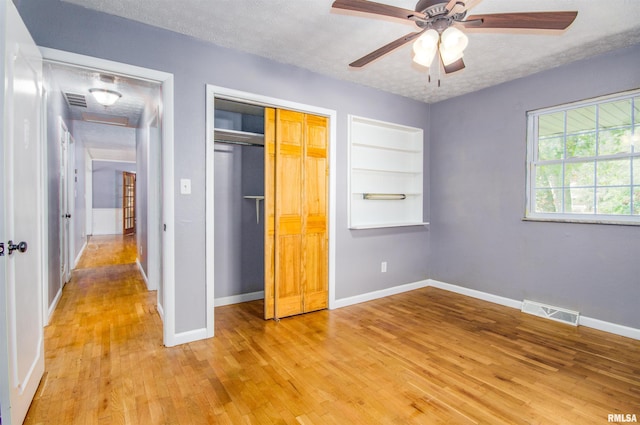 unfurnished bedroom featuring ceiling fan, a closet, light hardwood / wood-style floors, and a textured ceiling