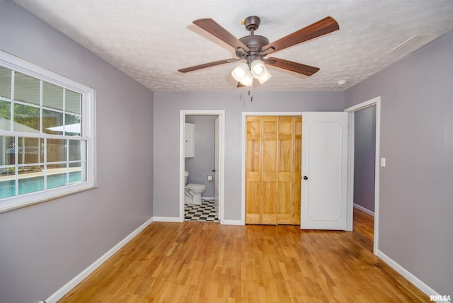 unfurnished bedroom with connected bathroom, ceiling fan, light hardwood / wood-style flooring, a textured ceiling, and a closet