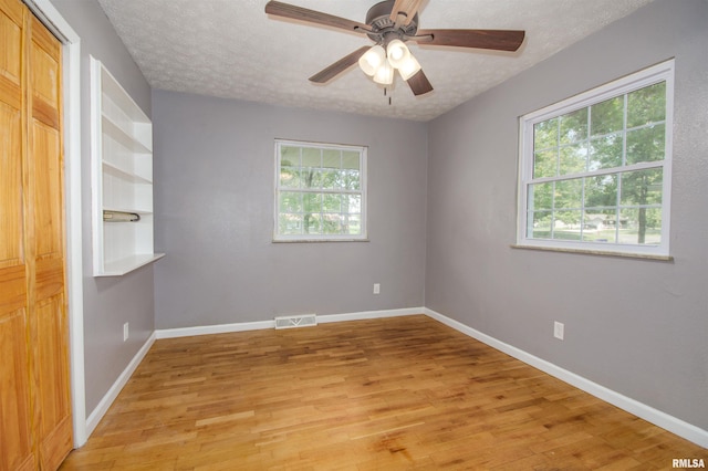 unfurnished room featuring a wealth of natural light, light hardwood / wood-style flooring, and a textured ceiling