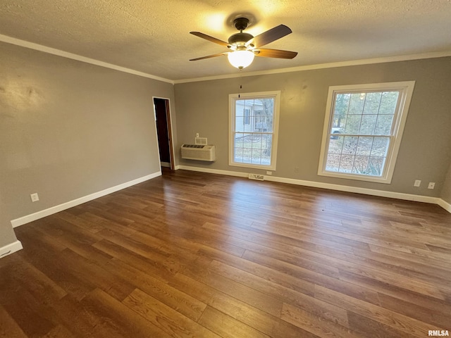 empty room with a textured ceiling, a wall mounted air conditioner, a healthy amount of sunlight, and dark hardwood / wood-style floors