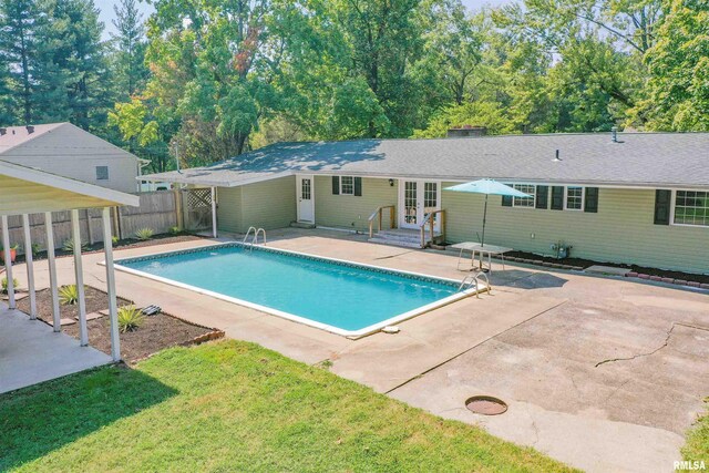 view of swimming pool featuring a patio area, a yard, and french doors