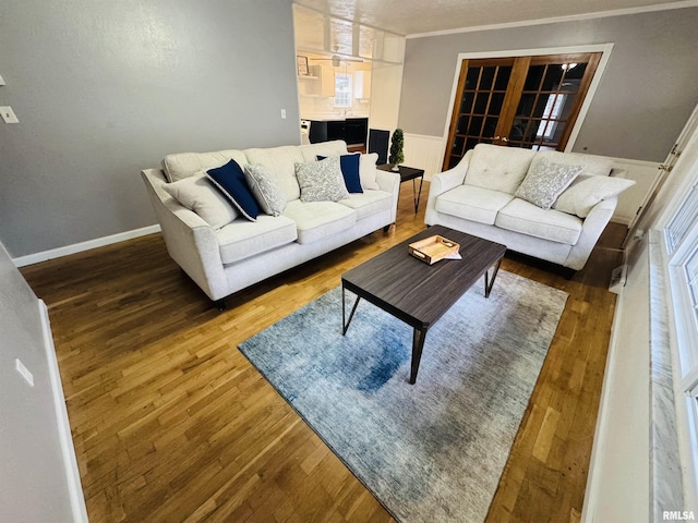 living room featuring wood-type flooring, ornamental molding, and french doors