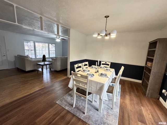 dining room with dark hardwood / wood-style flooring, ceiling fan with notable chandelier, and a textured ceiling