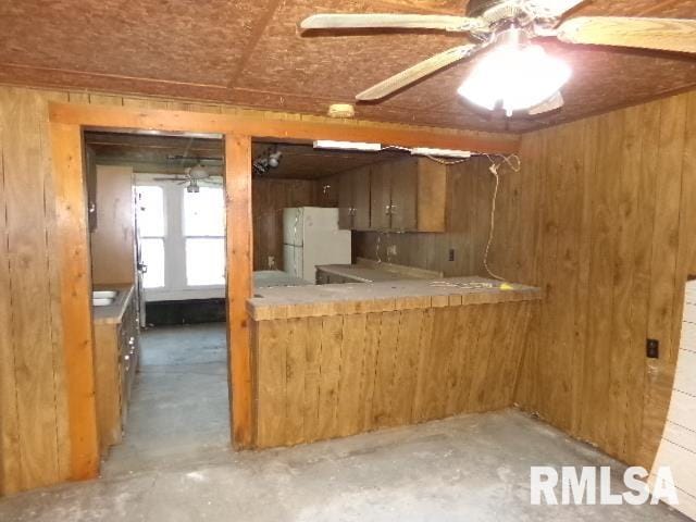 318 Williams St, Rosiclare, IL 62982 - kitchen featuring white fridge, wooden walls, concrete floors, and ceiling fan