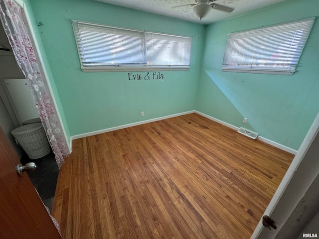 unfurnished room with a healthy amount of sunlight, ceiling fan, and hardwood / wood-style floors