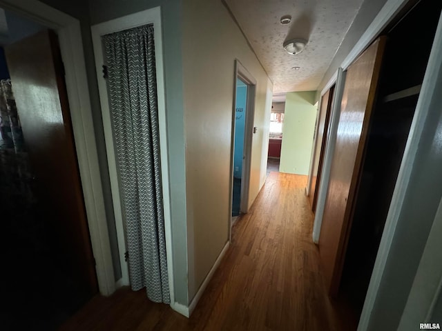 hall featuring a textured ceiling and hardwood / wood-style floors