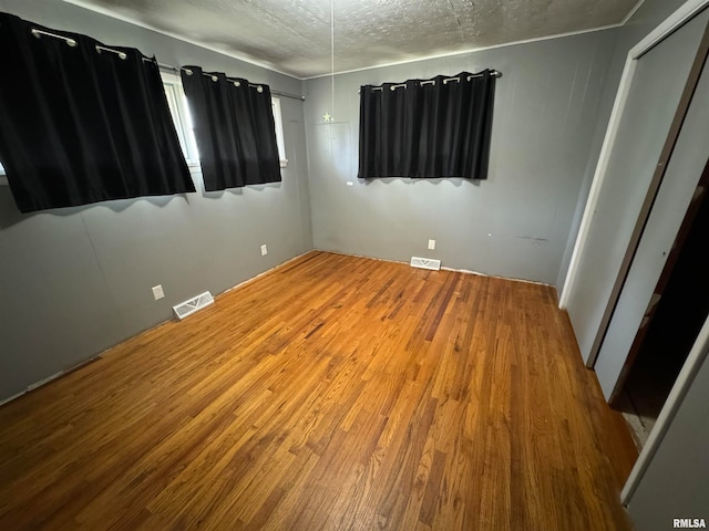 spare room with a textured ceiling and wood-type flooring