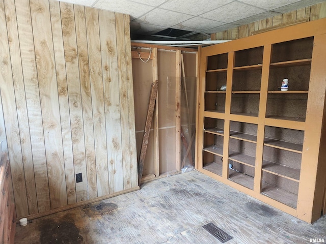 basement featuring wooden walls and a drop ceiling