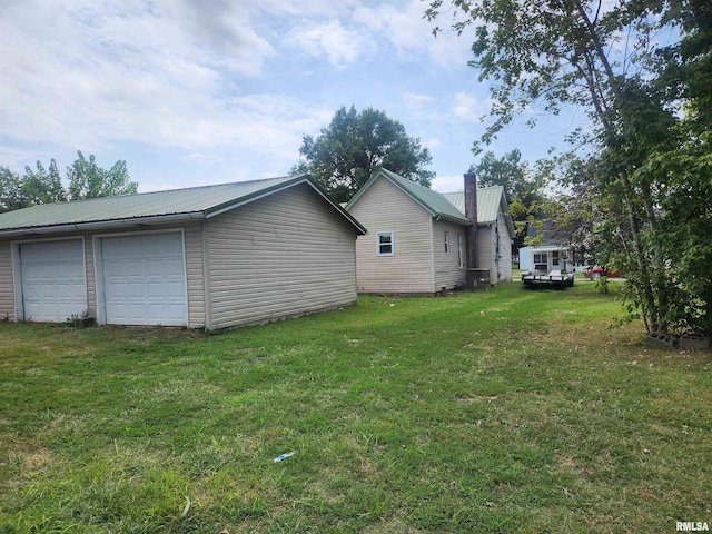 view of yard featuring a garage and central AC unit