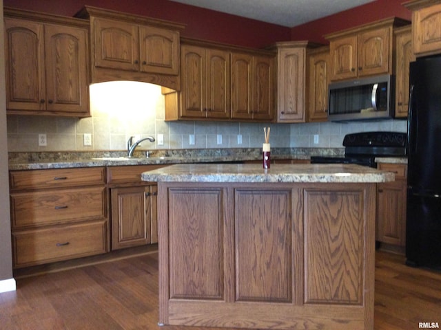 kitchen with black appliances, a center island, dark wood-type flooring, sink, and decorative backsplash