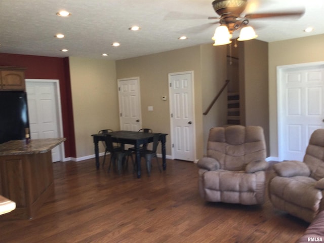 living room featuring ceiling fan and dark hardwood / wood-style floors