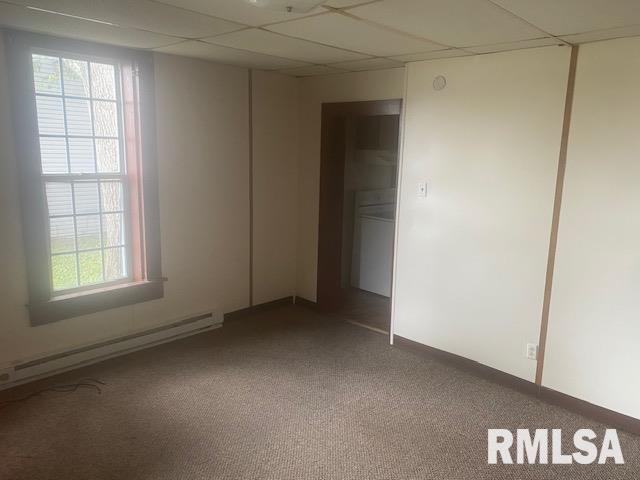 unfurnished room with baseboard heating, a paneled ceiling, and carpet flooring