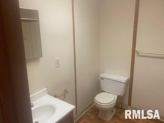 bathroom with vanity, toilet, and parquet flooring