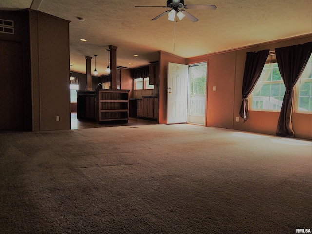 unfurnished living room featuring a textured ceiling, carpet flooring, and ceiling fan