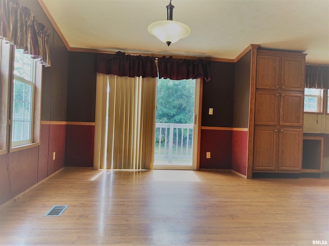 unfurnished room with a healthy amount of sunlight, ornamental molding, and light hardwood / wood-style floors