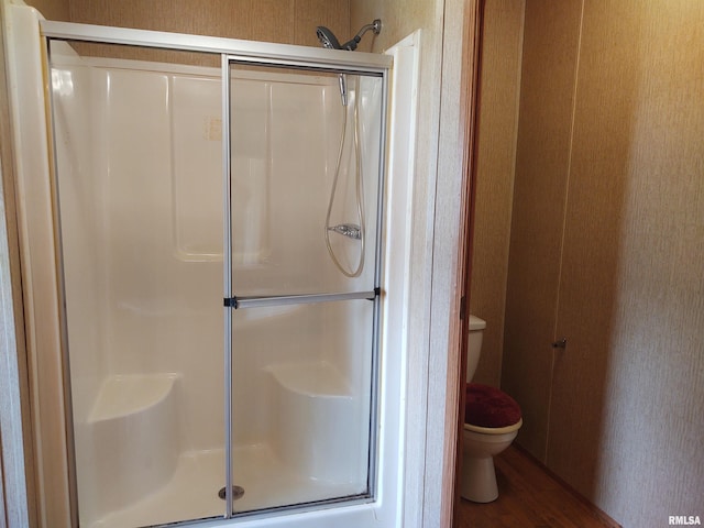 bathroom featuring toilet, an enclosed shower, and hardwood / wood-style flooring