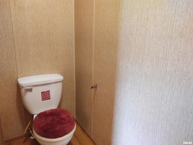 bathroom featuring toilet, hardwood / wood-style floors, and wood walls