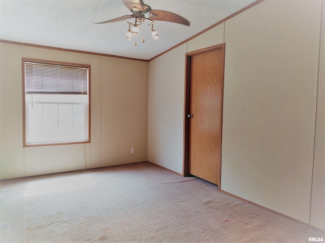 interior space with vaulted ceiling, light carpet, ceiling fan, ornamental molding, and a textured ceiling