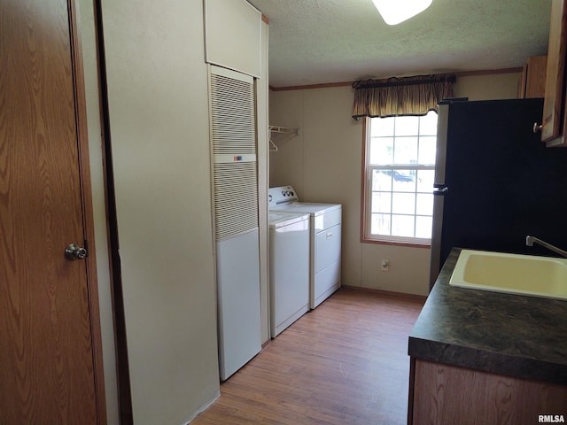 washroom with a textured ceiling, light hardwood / wood-style flooring, sink, separate washer and dryer, and ornamental molding