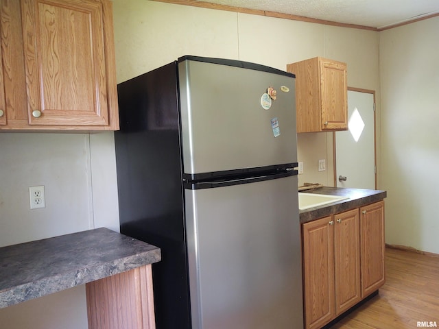 kitchen with ornamental molding, stainless steel fridge, and light hardwood / wood-style flooring