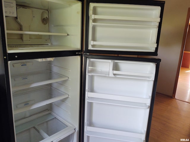 room details with hardwood / wood-style flooring and white fridge