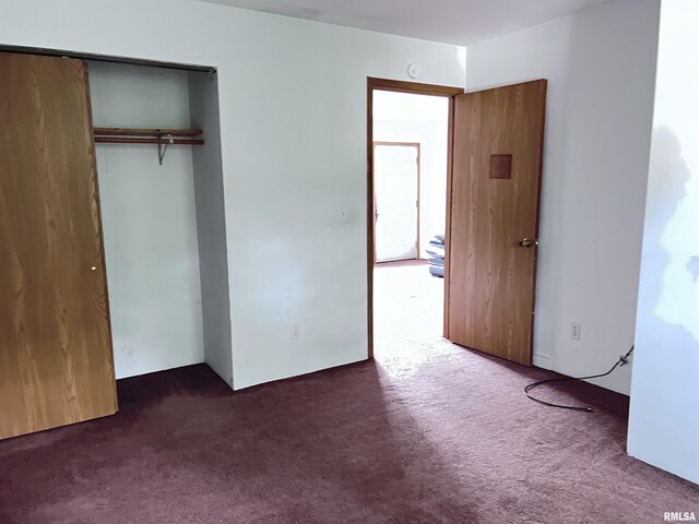 unfurnished bedroom featuring dark colored carpet and a closet