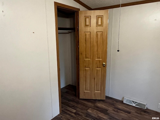 interior space with a textured ceiling, dark hardwood / wood-style flooring, and a closet