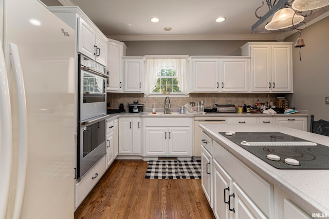 kitchen with dark hardwood / wood-style floors, backsplash, sink, white cabinetry, and black electric cooktop