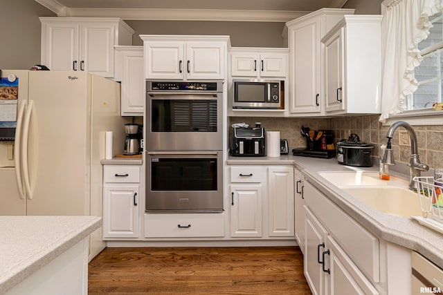 kitchen with dark hardwood / wood-style flooring, backsplash, stainless steel appliances, sink, and white cabinets