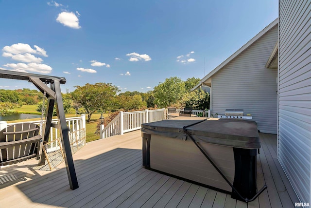 wooden deck featuring a water view and a hot tub