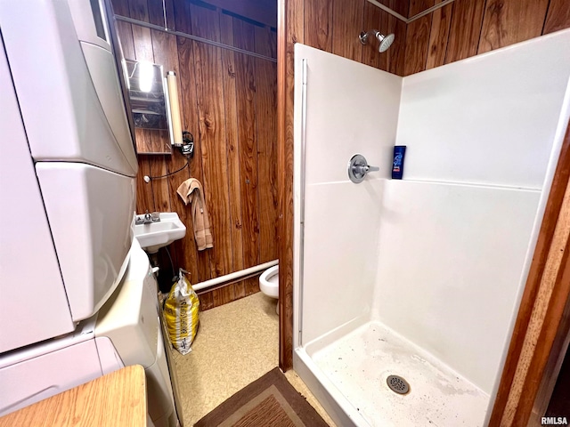 bathroom with wood walls, toilet, sink, and walk in shower