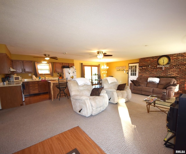 carpeted living room with brick wall, a healthy amount of sunlight, ceiling fan, and sink