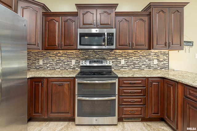 kitchen with appliances with stainless steel finishes, backsplash, visible vents, and light stone countertops