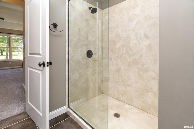 full bath featuring tile patterned flooring, baseboards, and a walk in shower