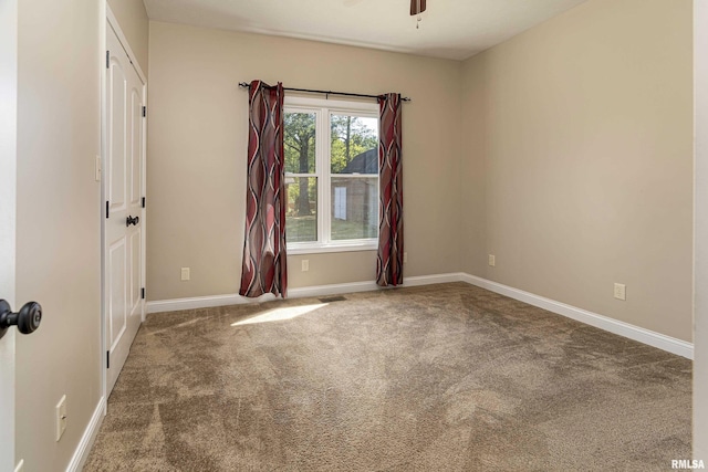 carpeted spare room with a ceiling fan, visible vents, and baseboards