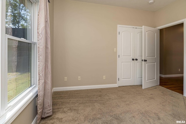 unfurnished room featuring carpet and baseboards