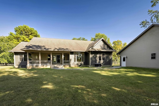 rear view of house with central air condition unit, covered porch, a shingled roof, and a lawn