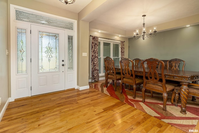 dining area with a notable chandelier, baseboards, and light wood-style floors