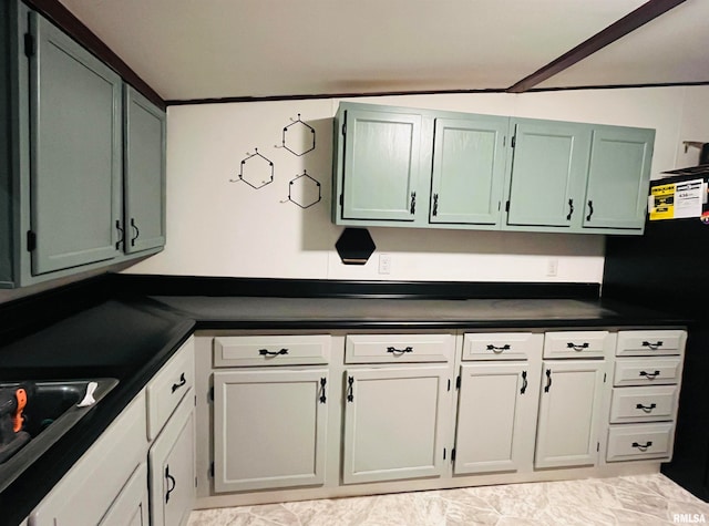 kitchen featuring ornamental molding, green cabinetry, sink, and black fridge