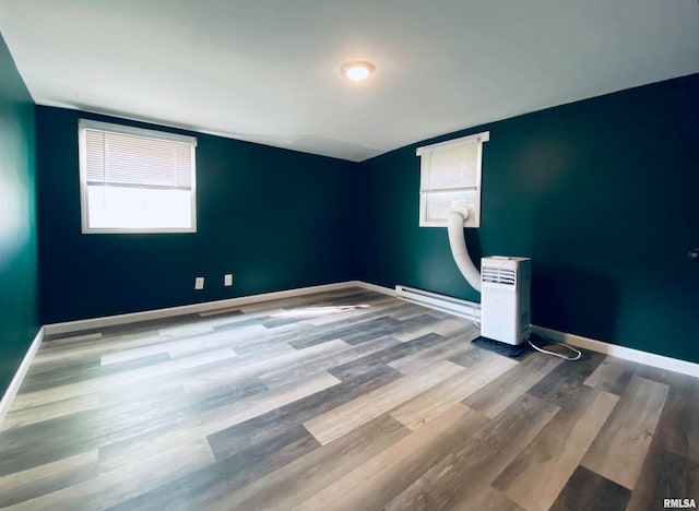 unfurnished room featuring wood-type flooring and a baseboard radiator