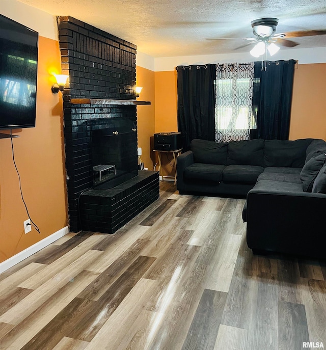 living room with a textured ceiling, ceiling fan, hardwood / wood-style floors, and a fireplace